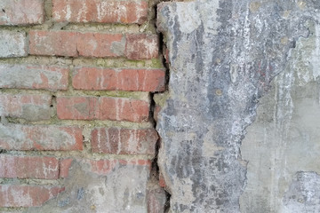 A brick wall with a crack dividing it in half. A break in the brickwork.