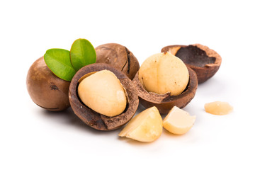 Macadamia nut with pieces and green leaves isolated on a white background