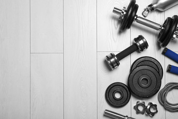 Gym equipment on wooden floor, flat lay. Space for text