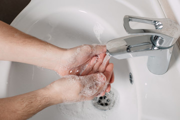 Hygiene concept. Washing hands with soap under the tap with water. handsome male hands and water in the bathroom.