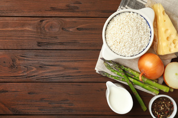 Flat lay composition with different ingredients on wooden table, space for text. Risotto recipe