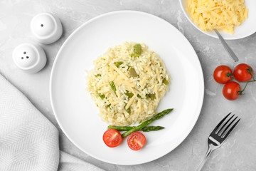 Delicious risotto with asparagus and tomatoes on grey marble table, flat lay