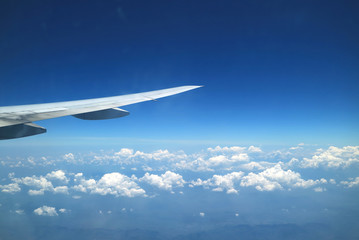 Stunning view of vivid blue sky and pure white clouds with airplane wing seen from plane window during flight