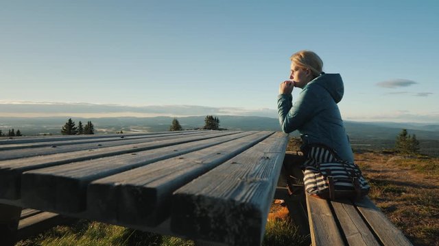 A lonely middle-aged woman sitting at a table high in the mountains, prays.