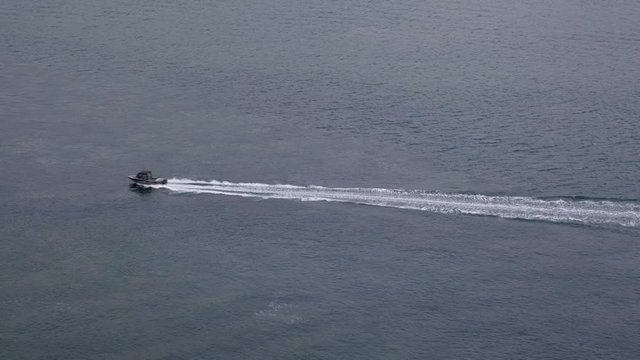 Small speedboat zipping through the sea on a cold winter day, exiting frame from the left (4K)