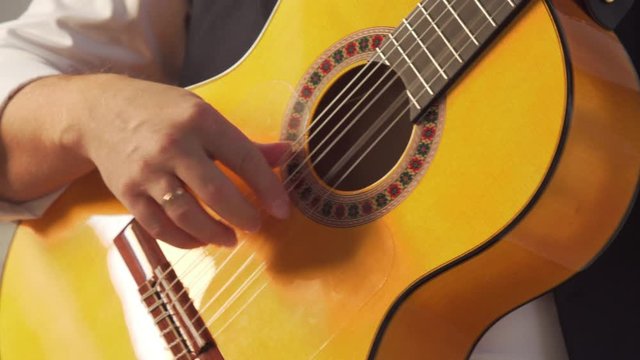 Man in a white shirt plays a classical guitar close-up