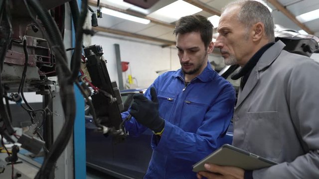 Apprentice working in automotive workshop