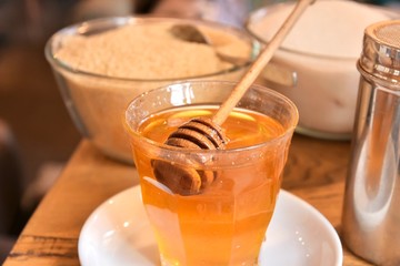 Additives to hot drinks.  Cane sugar, white sugar and honey with a special wooden spoon with...