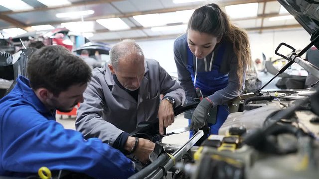Instructor with trainees working on car engine 