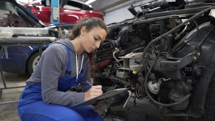 Young woman apprentice working in mechanics workshop