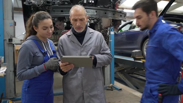 Trainee with mechanics manager working on car technology