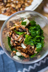 Green Italian pesto ingredients - traditional dip paste sauce with walnuts, garlic and basil leaves in glass jar. Vegan food.