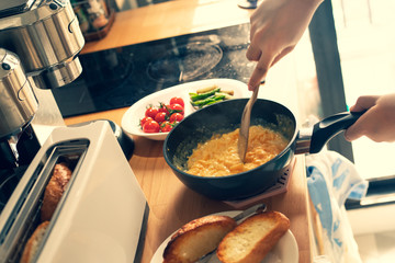 Selective focus of female cooking breakfast on kitchen counter bar in morning