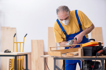 Old male carpenter working in workshop