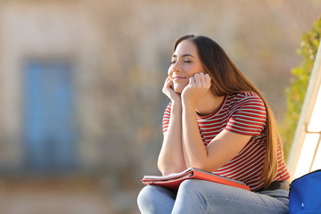 Happy student relaxing sitting in a campus