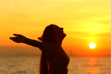 Happy woman celebrating day stretching arms at sunrise