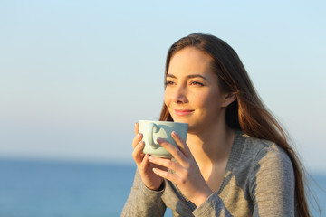 Relaxed woman drinking coffee looking away at sunset