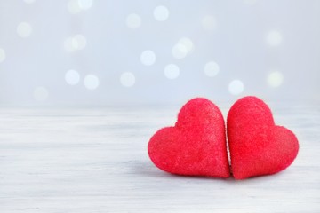 Obraz premium Two closeup love hearts on a wooden table and blurry defocused light bokeh background. Valentine's day greeting card. Love and holiday concept. Copy space for text.