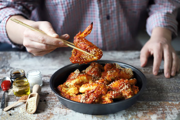 Selective focus. Man eats with chopsticks chicken wings. Chinese style chicken wings with sesame seeds.