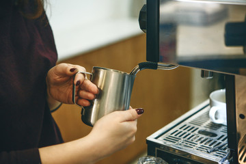 Fototapeta na wymiar The process of making cappuccino in a coffee machine. Barista pours milk to add to coffee