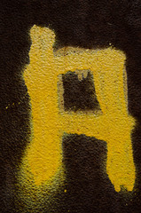 Buchstabe A mit gelber Farbe auf rostigen Hintergrund gesprüht