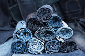 Rolled jeanses of different shades on denim background. Close-up