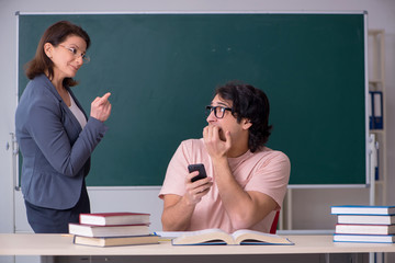 Old female teacher and male student in the classroom