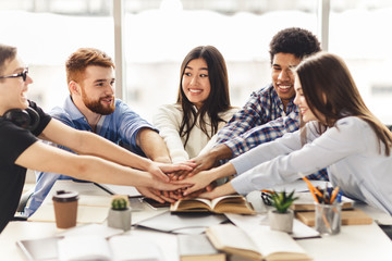 Happy groupmates placing hands together to show their unity