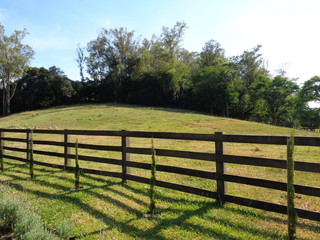 Fototapeta na wymiar Fence in field. Hill view. Sunny day on the farm.