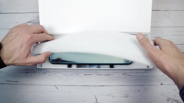 Man unpacking his parcel delivered from an e-commerce website. Young man taking a new purchased item from an envelope at home.
