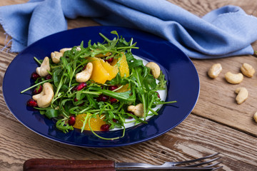 Vegan plant based salad with fresh  arugula, orange, pomegranate seeds, cashews