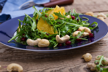Vegan plant based salad with fresh  arugula, orange, pomegranate seeds, cashews