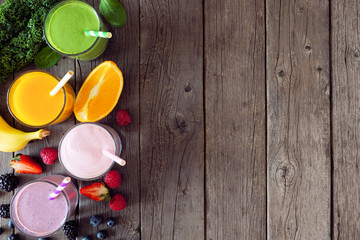 Assorted healthy fruit smoothies. Top view side border against a rustic wood background. Green, orange, strawberry and blueberry. Copy space.