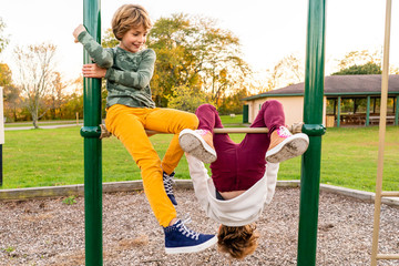 Young girls hanging upside down on playground equipment