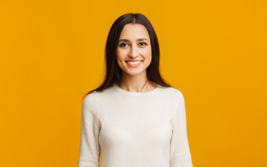 Portrait of beautiful arabic girl smiling while posing over yellow background