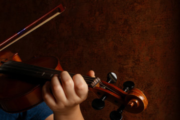 Child hands holding violin and playing symphony. Kid violinist playing music concept 