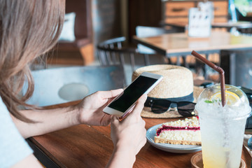 Close up of women's hands holding mobile phone in cafe..