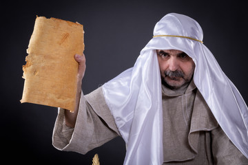 A man of eastern appearance engaged in occult sciences with a manuscript in his hands