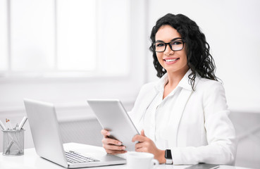 Portrait of happy latin girl using tablet and computer
