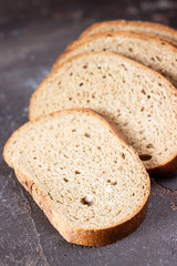Piece of rye bread with fungus (mold) on a dark brown slate background. 