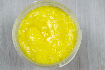 Macro scrub isolated on wooden background. Face body skin peeling sample. Yellow lemon scrub.