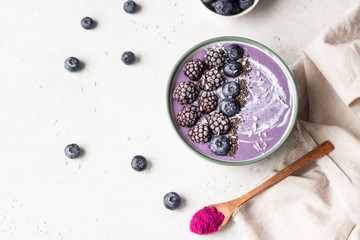 Smoothie bowl topped with blueberries, blackberries, chia seeds and coconut flakes. Healthy breakfast berry smoothie bowl.
