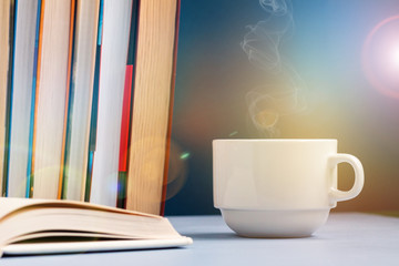 Coffee or tea cup on a table with stack of books and daily planner or copybook. Writer and business working day