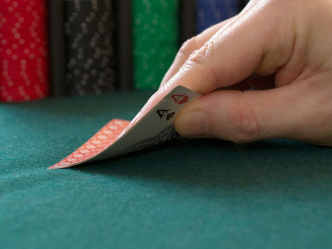 poker chips and ace of spades and ace of hearts on a green cloth casino table gamble