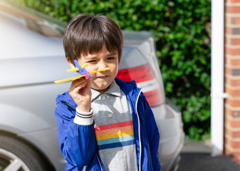 Portrait happy boy playing with toy airplane. Child throwing foam airplane, Kid playing outdoor in the summer