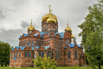 Fototapeta na wymiar Ancient orthodox church of red brick with golden domes.