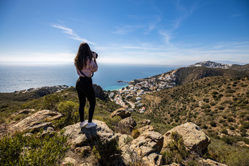 Beautiful woman photographer standing on a cliff taking a picture with a professional camera