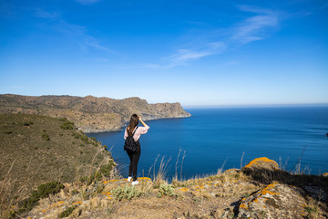 Beautiful woman standing on a cliff with the mediterranean sea in the background