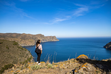 Beautiful woman standing on a cliff with the mediterranean sea in the background