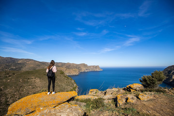 Beautiful woman standing on a cliff with the mediterranean sea in the background